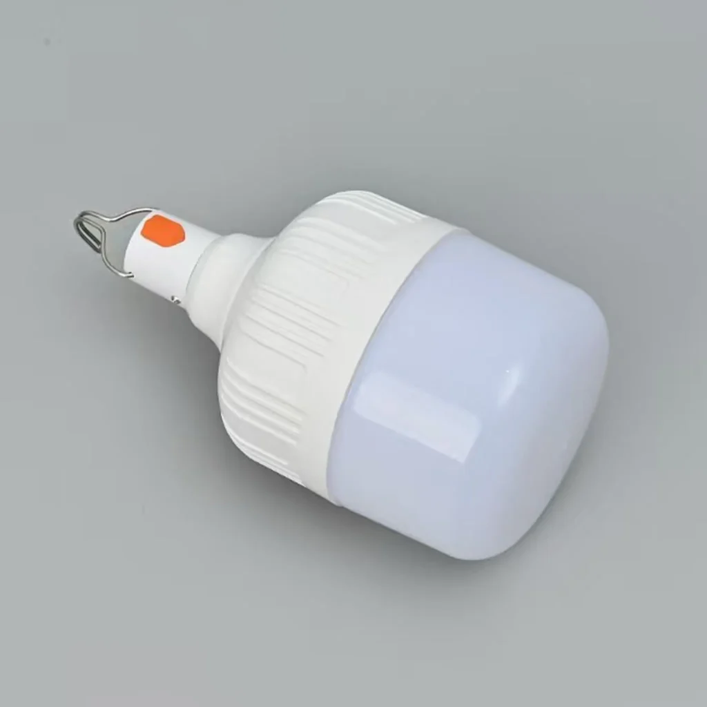 Bombilla LED portátil recargable de color blanco con gancho de metal para colgar, botón de encendido naranja y difusor opaco, sobre un fondo gris neutro.