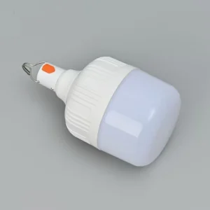 Bombilla LED portátil recargable de color blanco con gancho de metal para colgar, botón de encendido naranja y difusor opaco, sobre un fondo gris neutro.